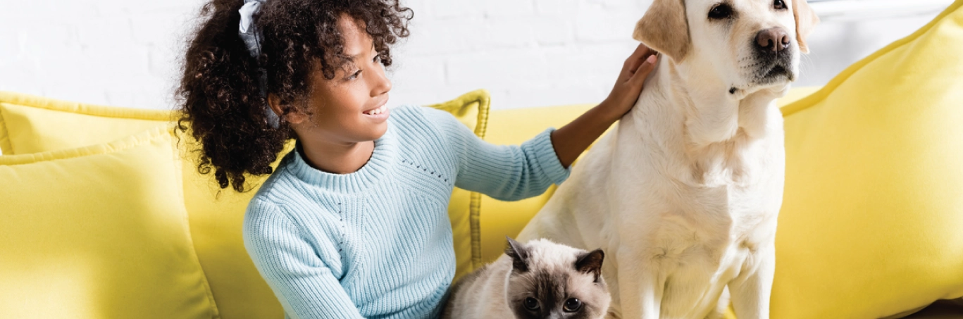 Young girl sitting out the couch with her dog and cat