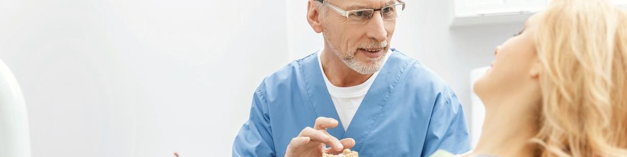 Dentist showing patient tooth model